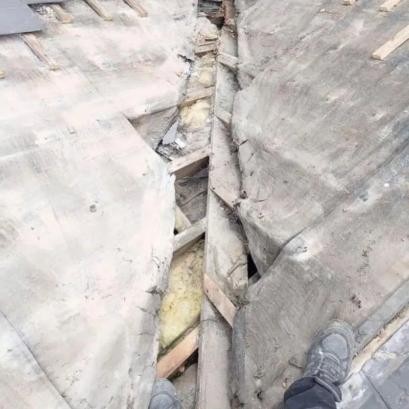 Exposed roof valley with torn underlay and timber visible beneath the removed slates