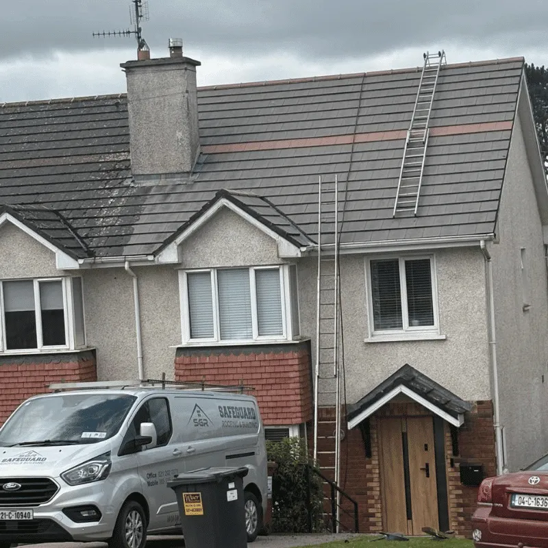 Tiled house roof with ladders in place and a Safeguard Roofing van parked outside
