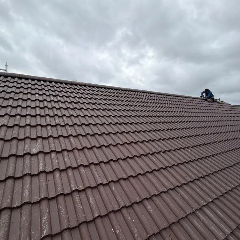 Completed brown tiled roof with half-round ridge tiles along the top